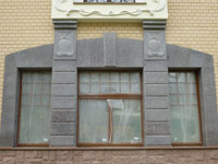 Окно частного дома, обрамленное гранитными рустами и барельефами